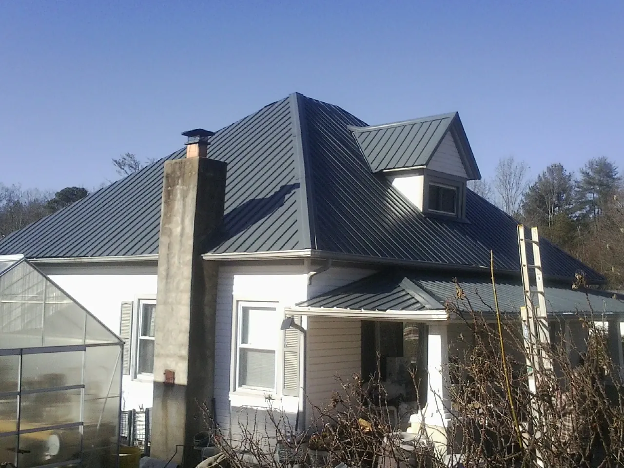 Dark blue standing seam metal roof on a white farmhouse with dormer — Slate & Tile Roof Repair by Roofing Brothers in Rutledge