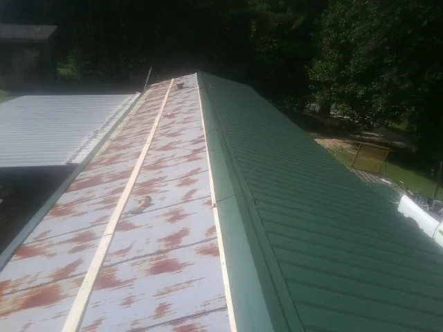 Old rusted panels beside newly installed green metal roofing — Wind Damage Roof Repair by Roofing Brothers in Rutledge