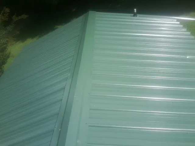 New green metal panels meeting at the ridge of a roof — Flat Roof Repair work by our crew in Rutledge