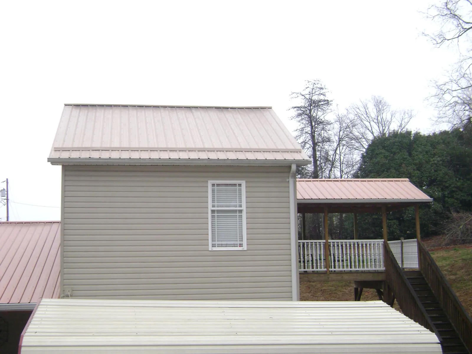 Tan metal roofs on a two story addition and attached porch, from a Roof Replacement job in Rutledge